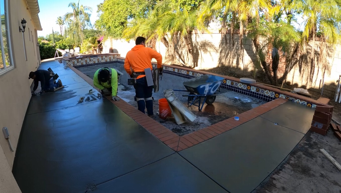 Crew finishing a concrete pool deck surface around a backyard pool in Tacoma, WA